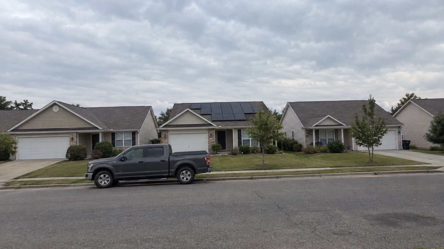 A row of suburban houses, one of them with solar panels on the roof